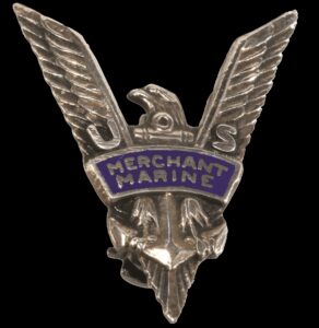 Silver tone V shaped pin in thee form of an eagle grasping an anchor with a blue banner reading Merchant Marine