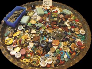 Oval mettal tray filled with colorful buttons, brooches, and other small items