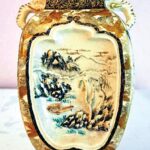 Colorful vase with a scenic panel with a mountain landscape and trees, elephant shaped handles, and square neck and base
