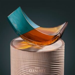 Spiral-shaped glass whisky bottle with a verdigris copper lid on a cylindrical platform