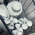 Overhead view of porcelain dishes with a flower pattern and a price marked in red in a shopping cart