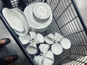 Overhead view of porcelain dishes with a flower pattern and a price marked in red in a shopping cart