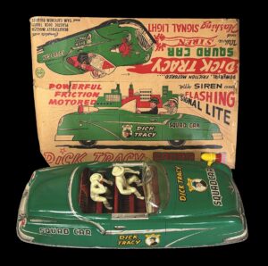 Green open top Dick Tracy toy car with 2 plastic figures in front of cardboard box