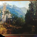 Large rectangular landscape painting with mountains in background and trees in foreground, patches of paint worn away