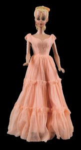 Doll with blond ponytail wearing salmon pink gown with long tiered skirt
