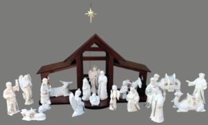 Nativity set with brown wood backdrop, pastel china figurines, and a metal star on a wire stand