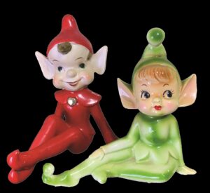 2 ceramic Christmas elves, seated, pointed hats, large ears, one dressed in red, one in light green