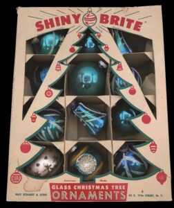 Box labeled "Shiny Brite" with a cutout Christmas tree showing a set of shiny teal ornaments inside