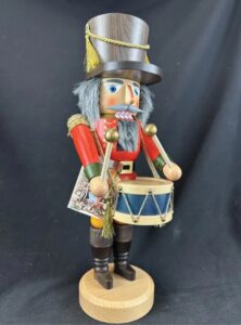 Figural nutcracker as a drummer with a wooden hat, red uniform, and blue snare drum